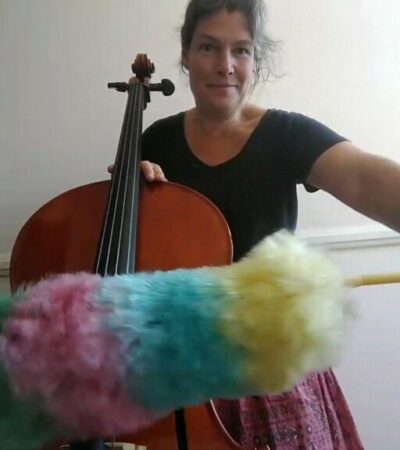 Woman maniacally playing a cello with a feather duster