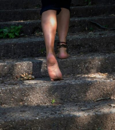 Bare feet ascending steps with plants growing on them